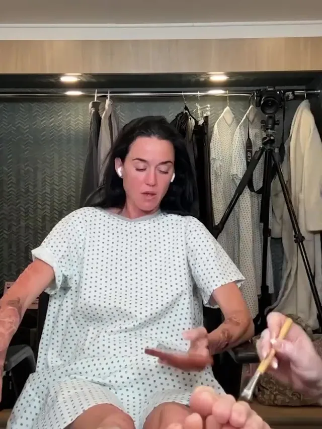 Katy Perry showing bare soles while seated in a makeup chair.