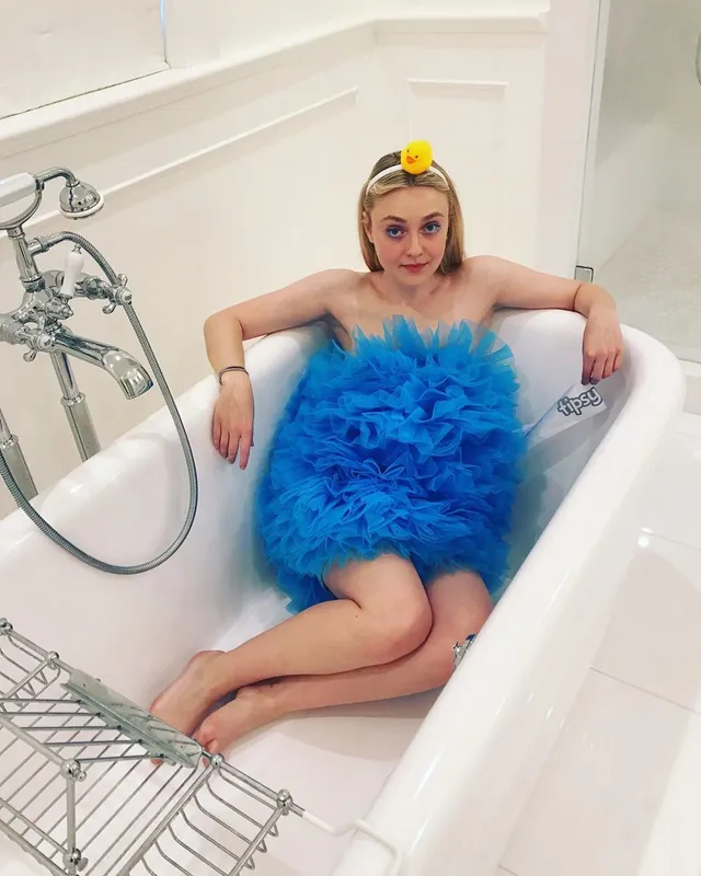Dakota Fanning sitting barefoot in a bathtub during a playful photo shoot.