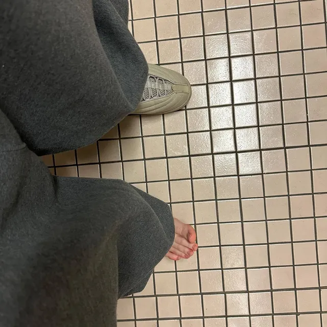 Billie Eilish a bare foot below loose grey trousers.