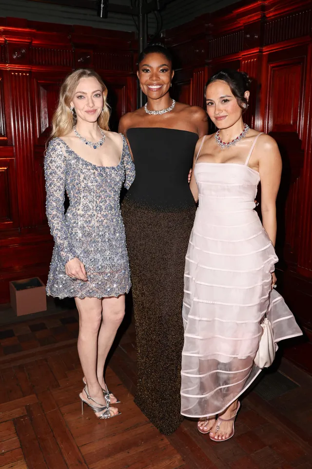 Amanda Seyfried posing with two guests in a sparkling dress and heels.