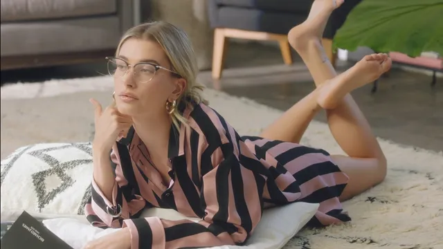 Hailey Bieber lying on a rug with bare feet raised.