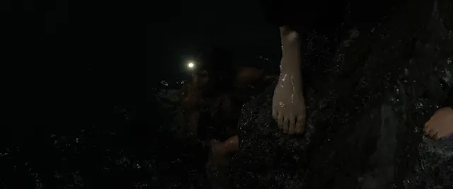Kathryn Newton with bare feet visible in a dimly lit outdoor film scene.