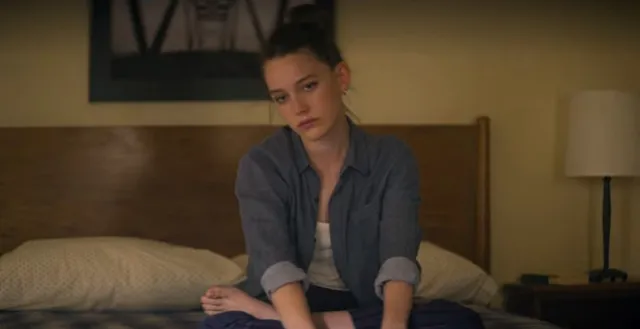 Victoria Pedretti sitting on a bed during a screen scene.