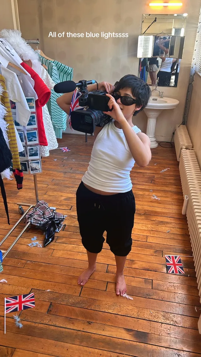 Naomi Scott posing barefoot in rehearsal clothes for a mirror photo.