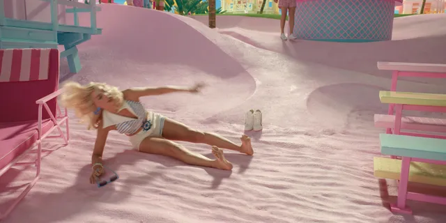 Margot Robbie stretching barefoot on a pink walkway in a film scene.