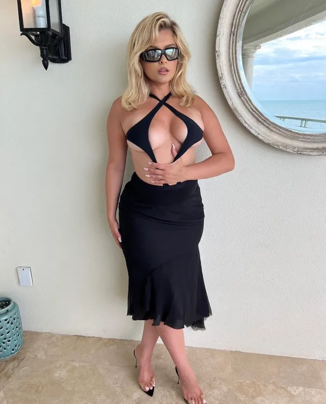 Bebe Rexha standing in a cut-out black dress and metallic heels.