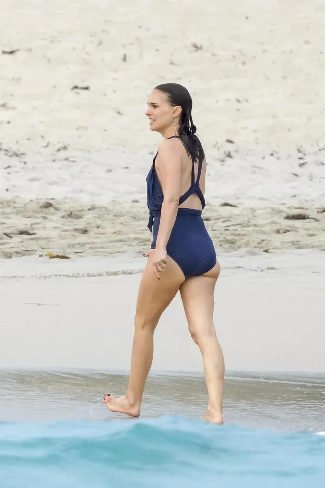 Natalie Portman walking barefoot along a beach.