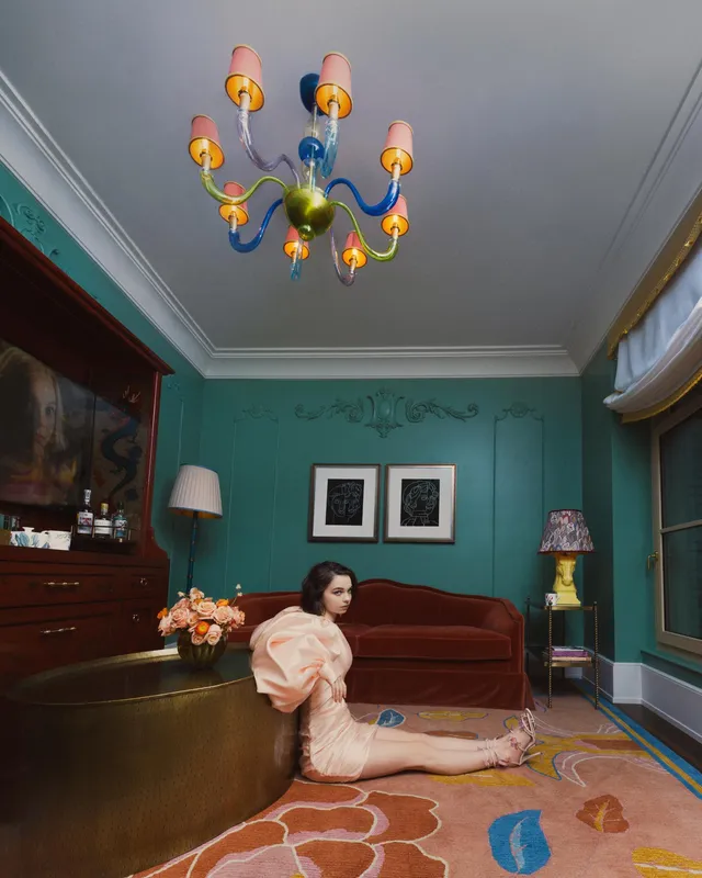 Emma Myers sitting on a floor in a pink dress and heels.