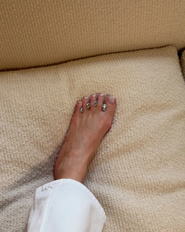 Rosie Huntington-Whiteley a bare foot resting on textured upholstery.