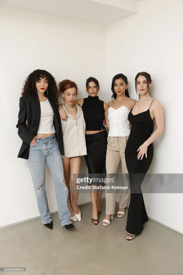 Adelaide Kane posing with companions at an event in a black dress.