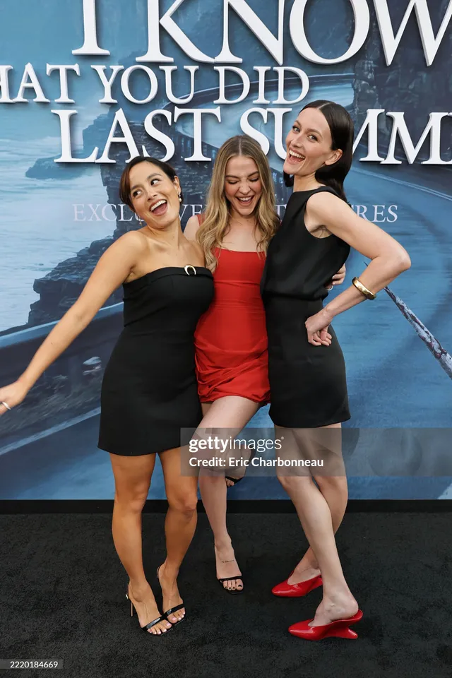 Chase Sui Wonders posing with cast members in a black dress and heels.
