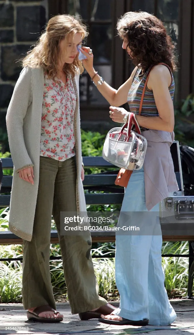 Kate Winslet standing outdoors in a floral top and coat beside a companion.