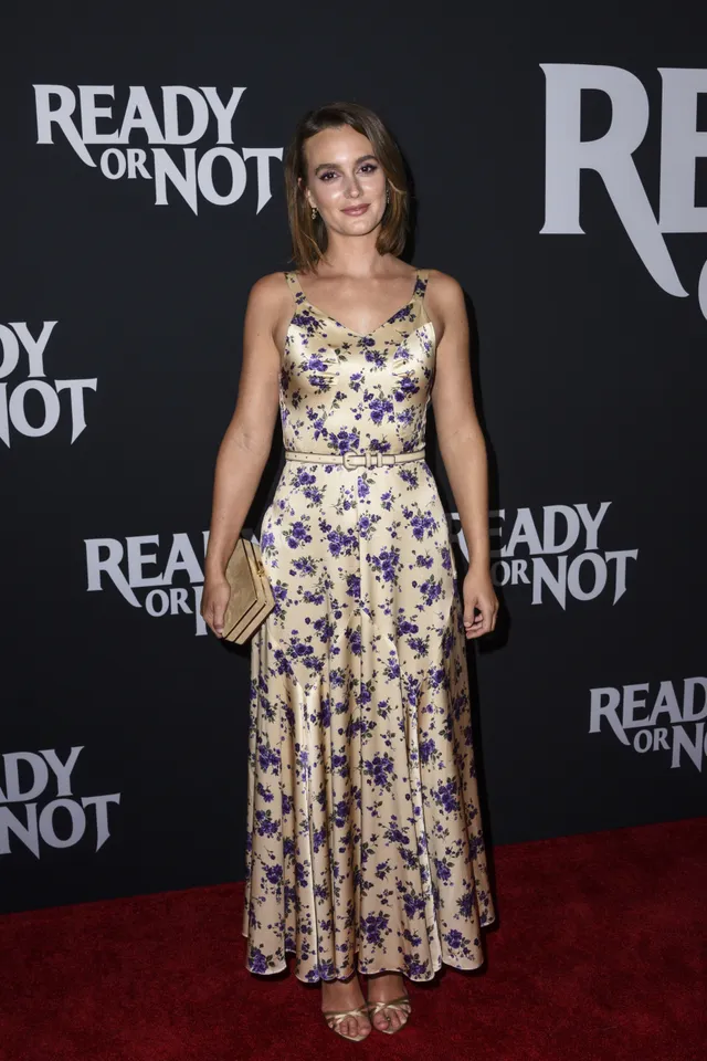 Leighton Meester posing at a premiere in a floral dress.