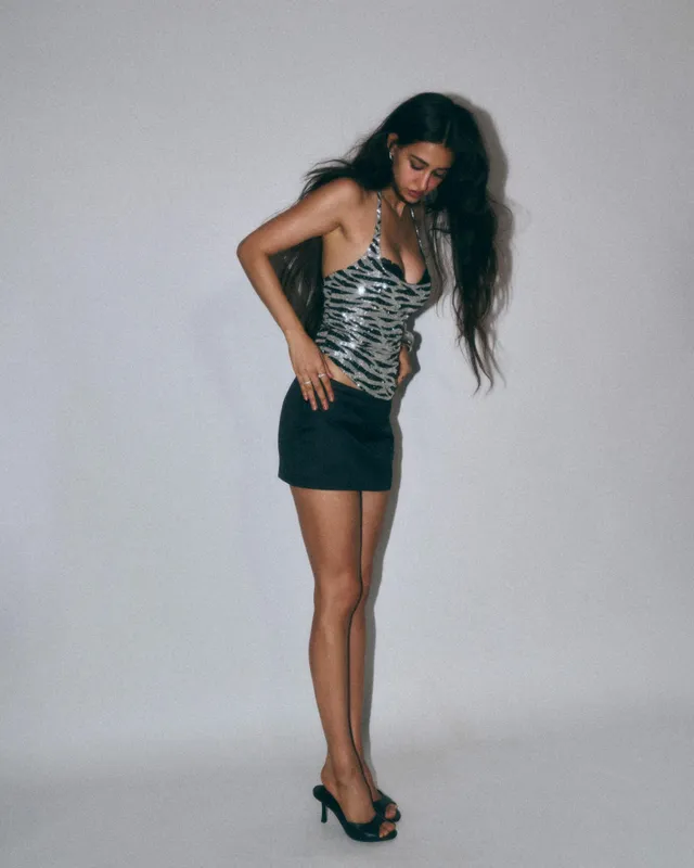 Disha Patani wearing black heeled sandals with a patterned top and short dark skirt.