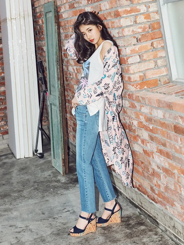 Bae Suzy wearing jeans and wedge heels by a brick wall.