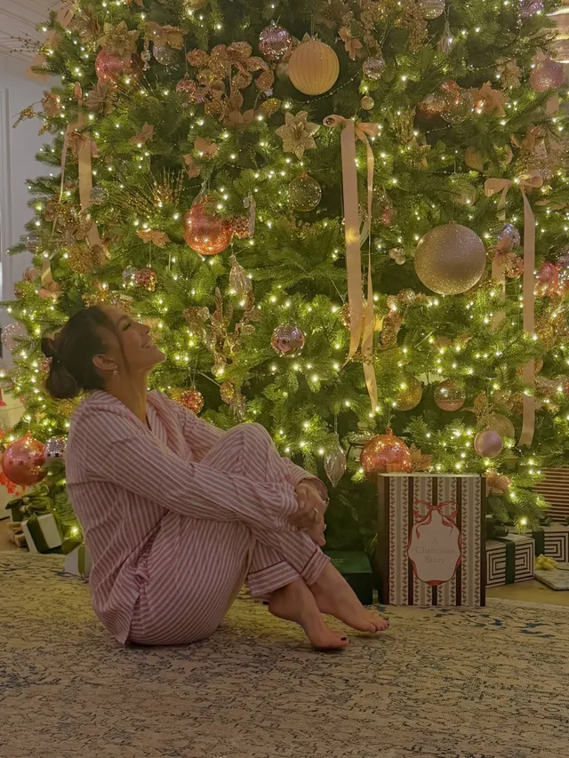 Jennifer Lopez a seated pyjama portrait beside a Christmas tree.