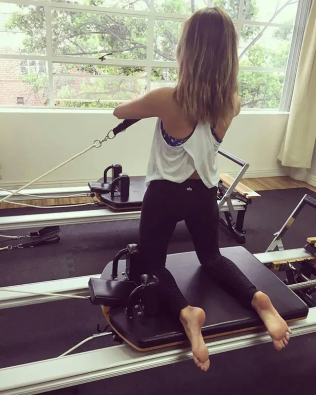 Debby Ryan using Pilates equipment with bare feet.