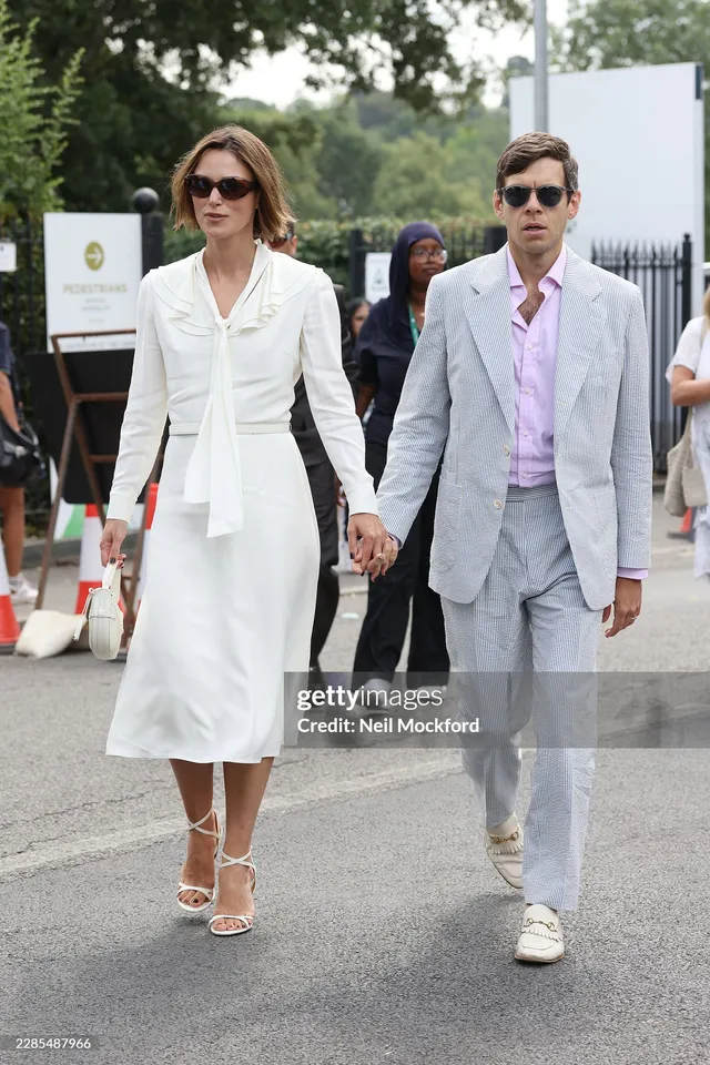 Keira Knightley walking beside a man wearing a white outfit and heels.