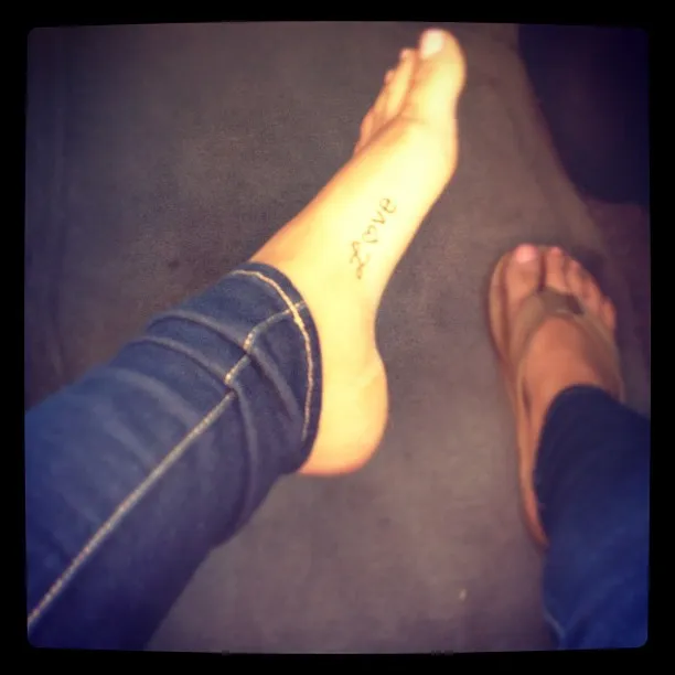 Ariana Grande showing an ankle tattoo in a close-up.