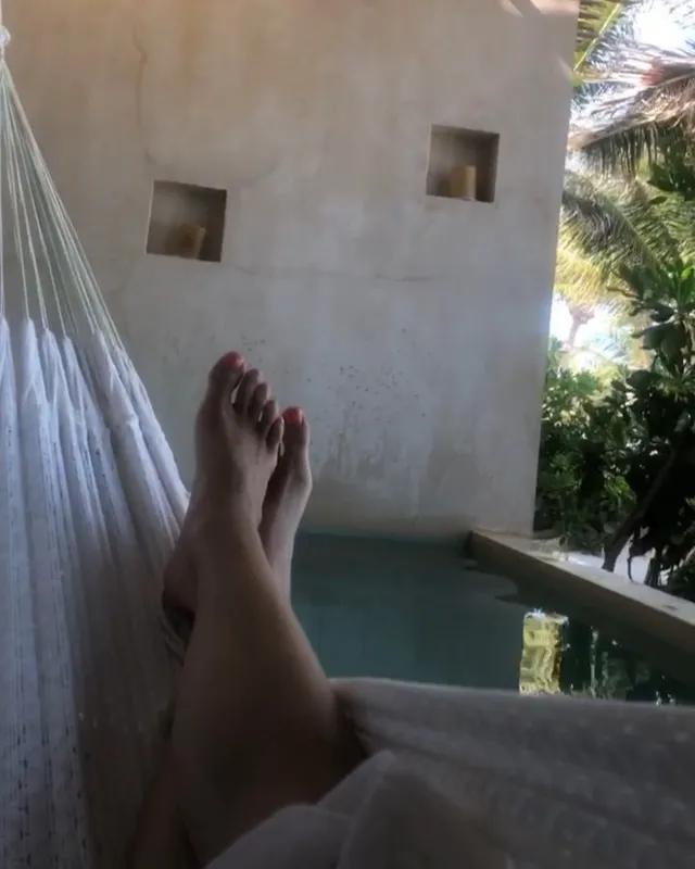 Maia Mitchell resting her bare feet beside a pool.