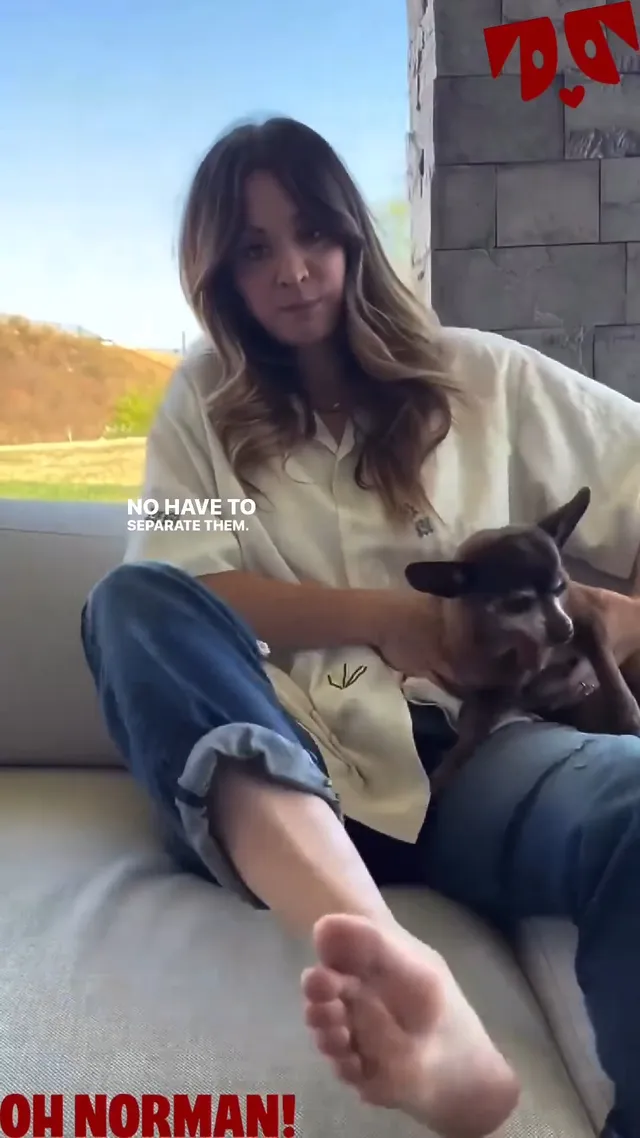 Kaley Cuoco sitting on a sofa with a dog and extending a bare sole toward the camera.