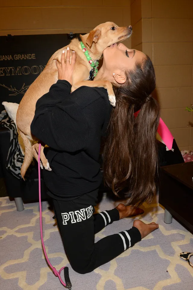 Ariana Grande holding a guest's foot while kneeling.