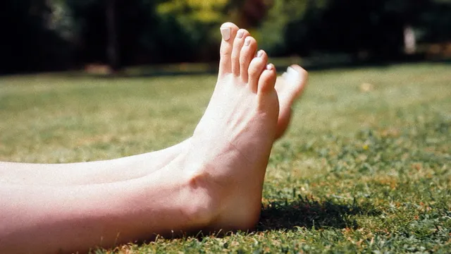 Daisy Edgar-Jones bare feet resting outdoors on grass.