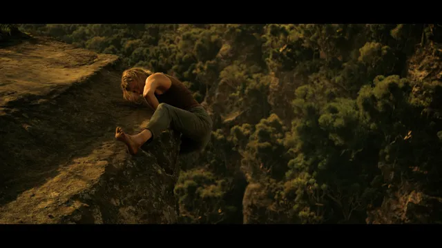 Charlize Theron a barefoot climbing screen scene beside a rock face.