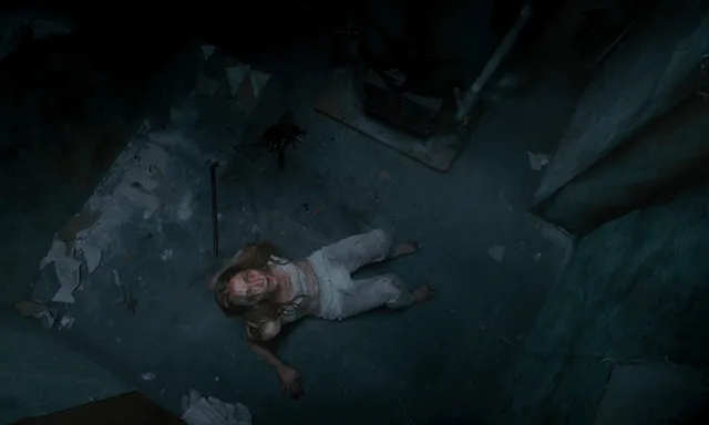Sophie Turner resting barefoot on a floor in a dimly lit scene.