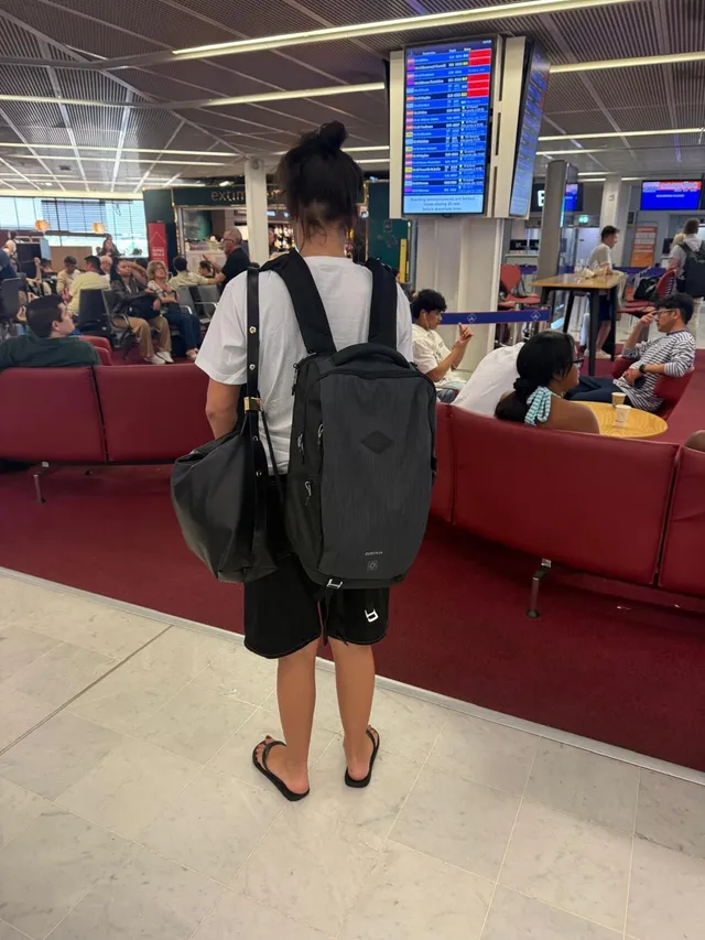 Adèle Exarchopoulos standing in an airport in flat black sandals.