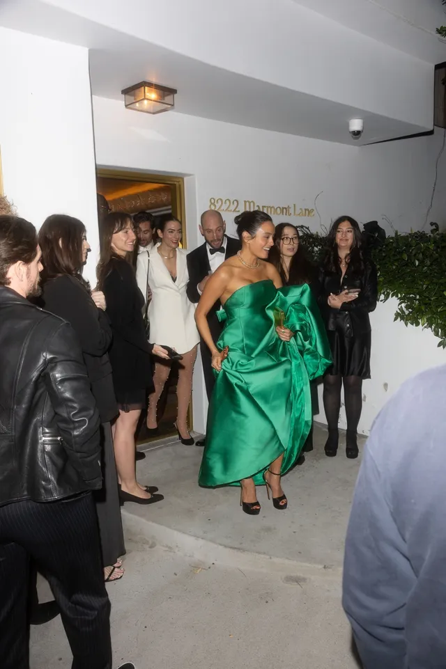 Chase Sui Wonders walking through a crowd in a green dress and black heels.