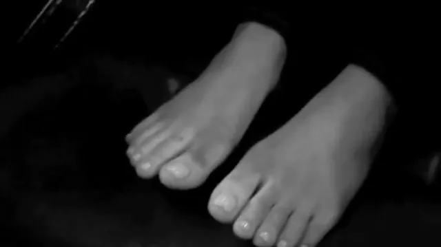 Ariana Grande: close view of bare feet in a monochrome photograph.