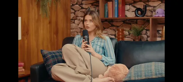 Nicole Wallace sitting cross-legged barefoot on a sofa during an interview.