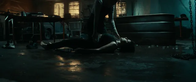 Dafne Keen lying barefoot on a floor in a film scene.