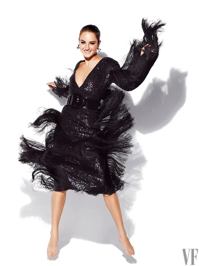 Grace Van Patten posing in a black feathered dress for a studio portrait.