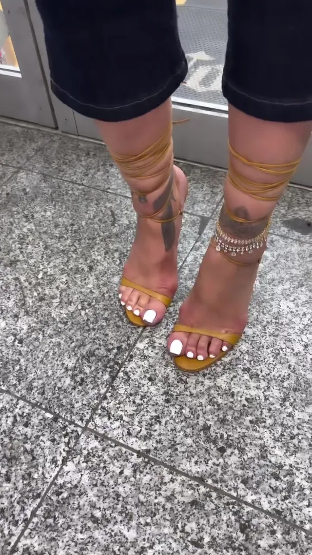 Rihanna showing yellow lace up heels beneath dark trousers.