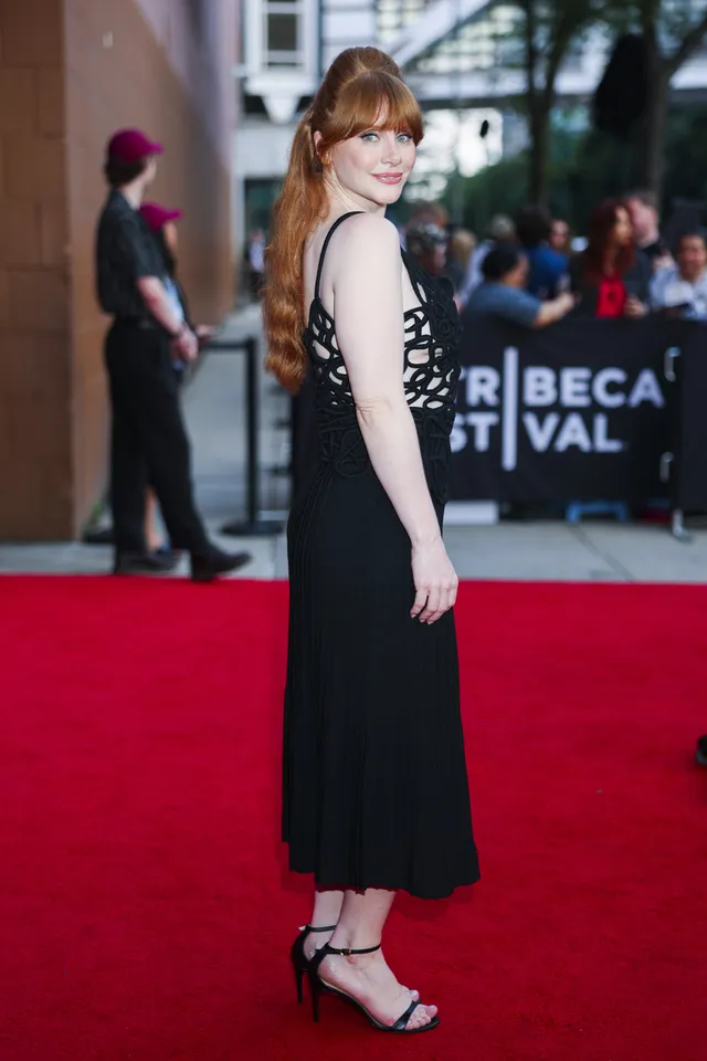 Bryce Dallas Howard posing on a red carpet in a black dress.