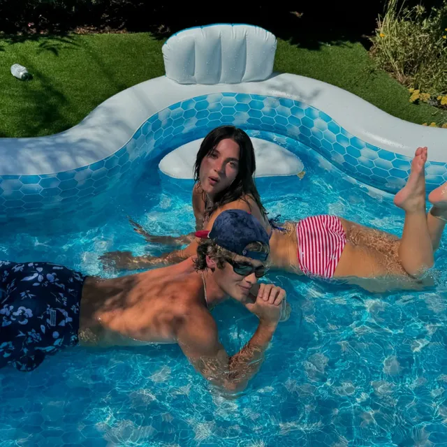 Mackenzie Ziegler floating in a pool with bare feet raised.
