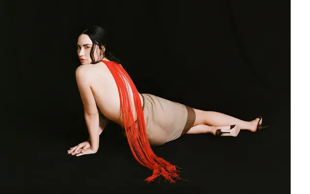 Demi Lovato reclining on a studio floor in a red outfit and nude heels.