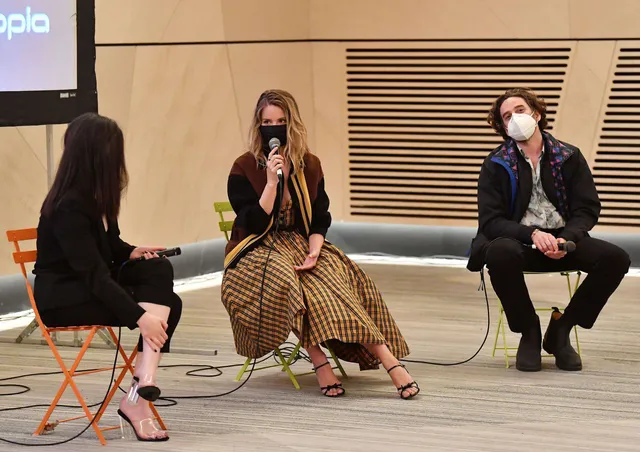 Dianna Agron sitting during a panel discussion in a patterned dress.