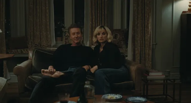Penélope Cruz a dimly lit seated screen scene beside a man.