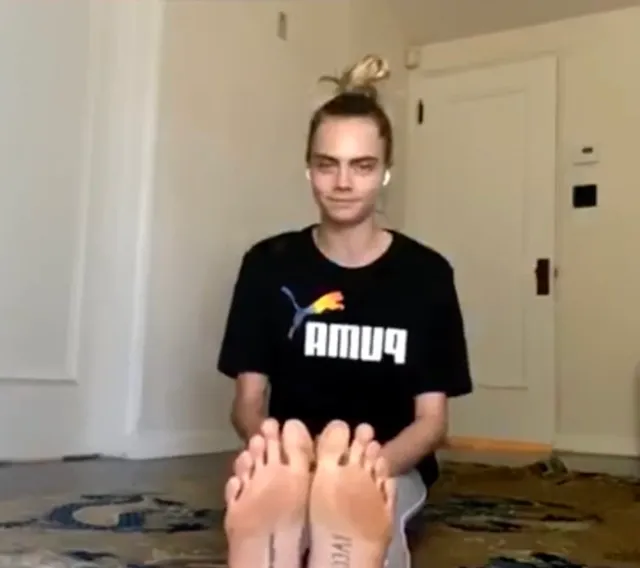 Cara Delevingne taking a playful photograph with her feet toward the camera.