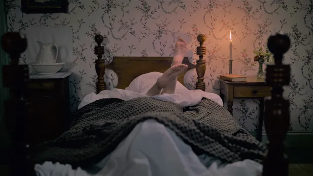 Hailee Steinfeld raising bare feet above patterned bedding.