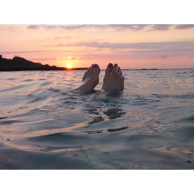 Anna Kendrick showing bare feet above the sea at sunset.