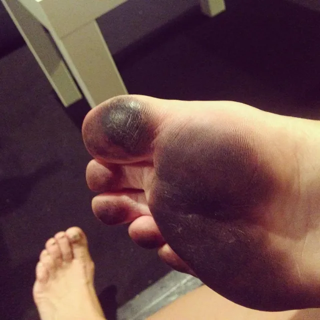 Tove Lo showing a bare sole with dark nail polish in a close-up photograph.