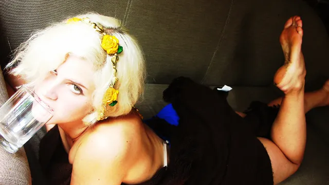 Lana Del Rey reclining indoors with a bare sole raised.