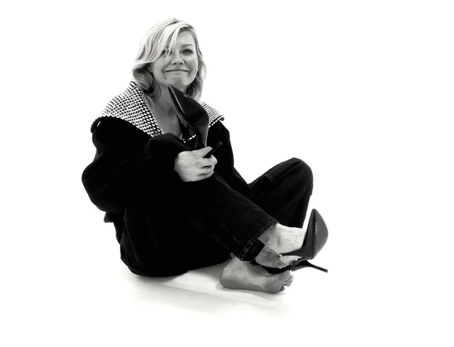 Kirsten Dunst sitting in a black outfit for a monochrome portrait.