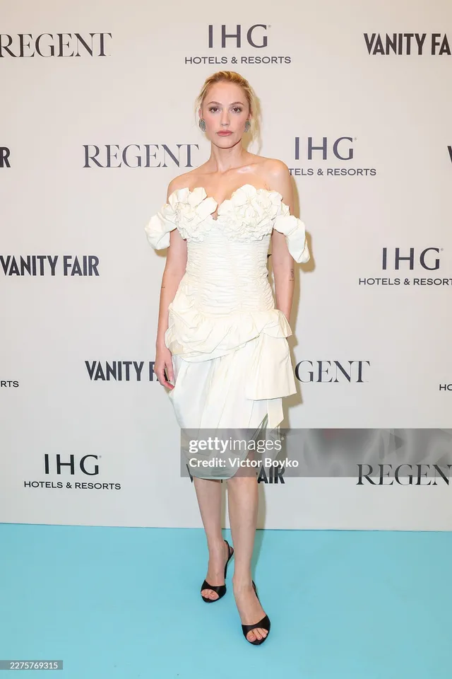Maika Monroe wearing a white dress and black heels at an event.