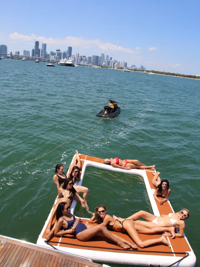 Jessica Alba reclining barefoot with a group on a floating platform.
