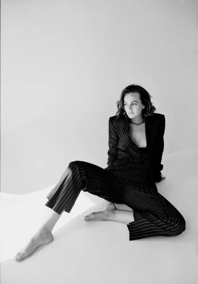 Leighton Meester sitting on the floor in a striped dark suit.